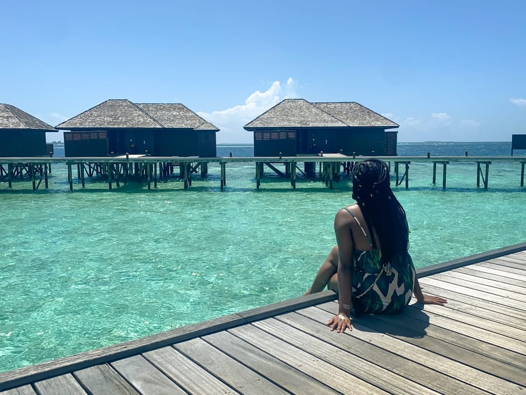 Girl sitting on boardwalk over the ocean at Lily Beach Resort and Spa, Maldives