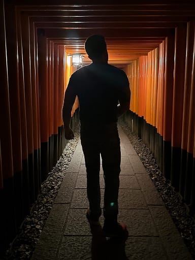Man walking through the Tori gates at night Fushimi Inari Shrine
