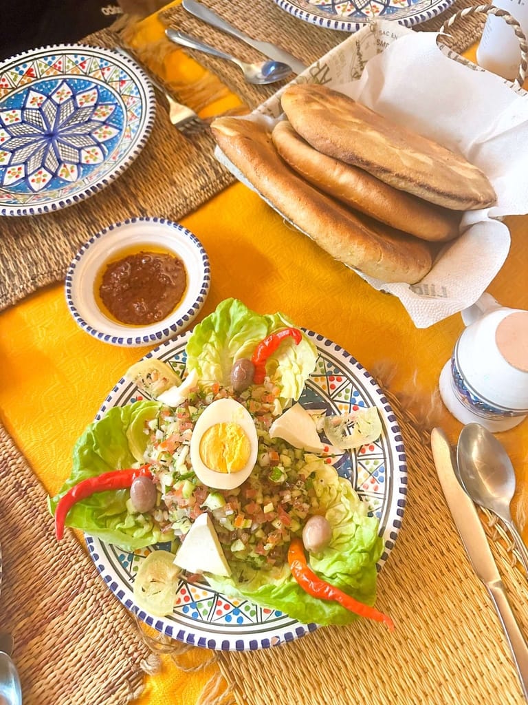 Dar jdoud dougga food that includes Tunisian salad, bread, and harissa.