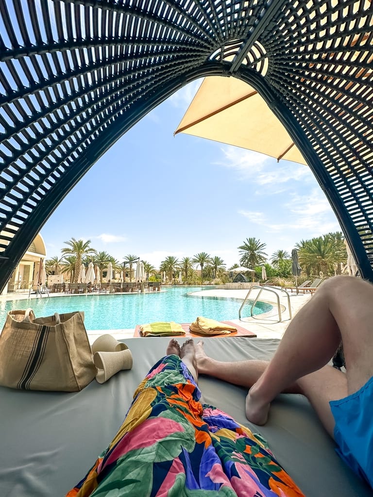 View of the Anantara pool from inside of a large wicker lounge chair.