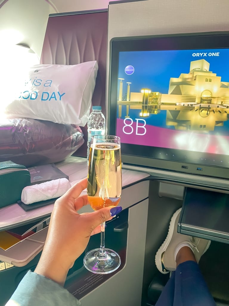 girl holding champagne in Qatar Airways Business class