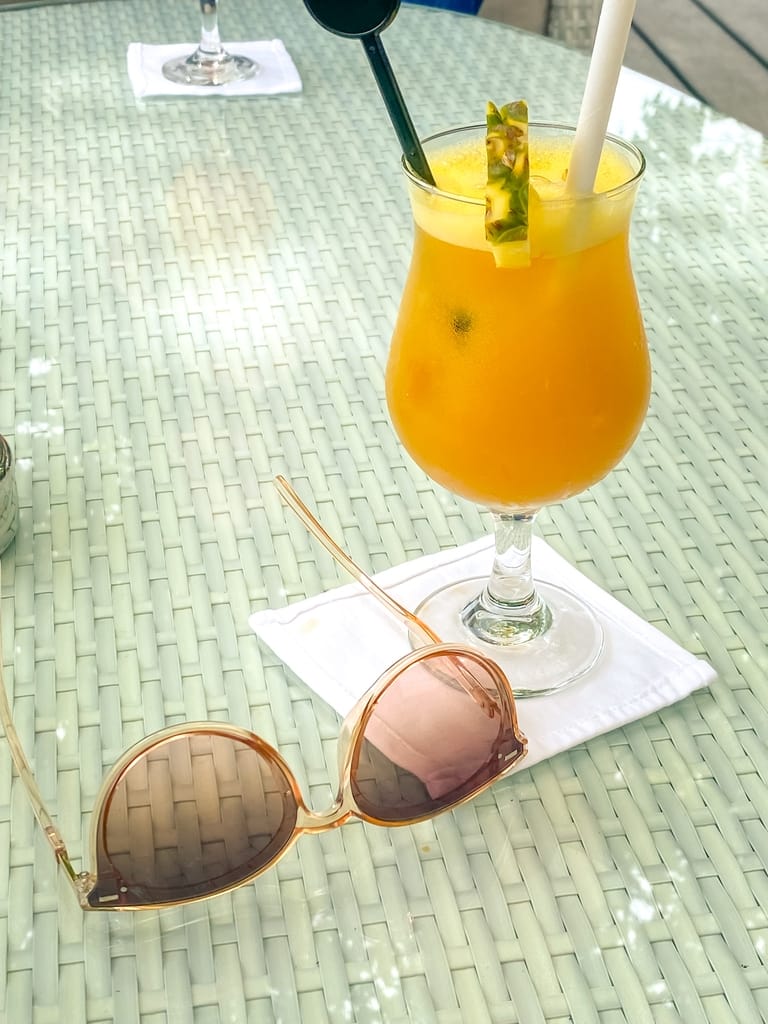 Pineapple cocktail and sunglasses on a table